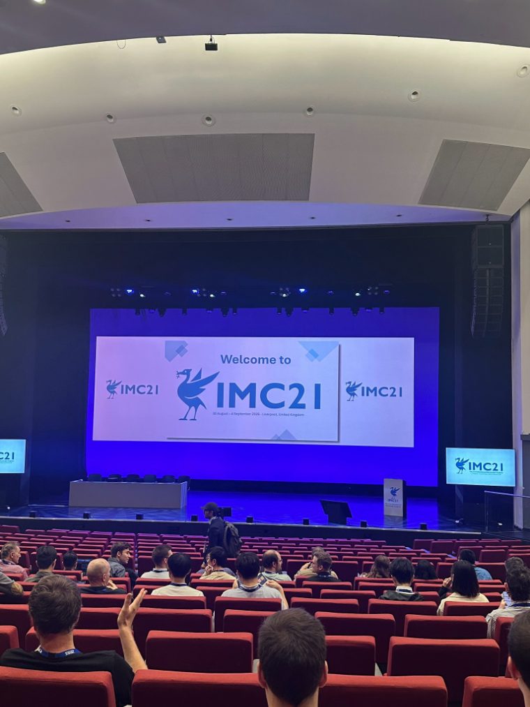 The IMC21 plenary hall with a Welcome to IMC21 slide on the main screen
